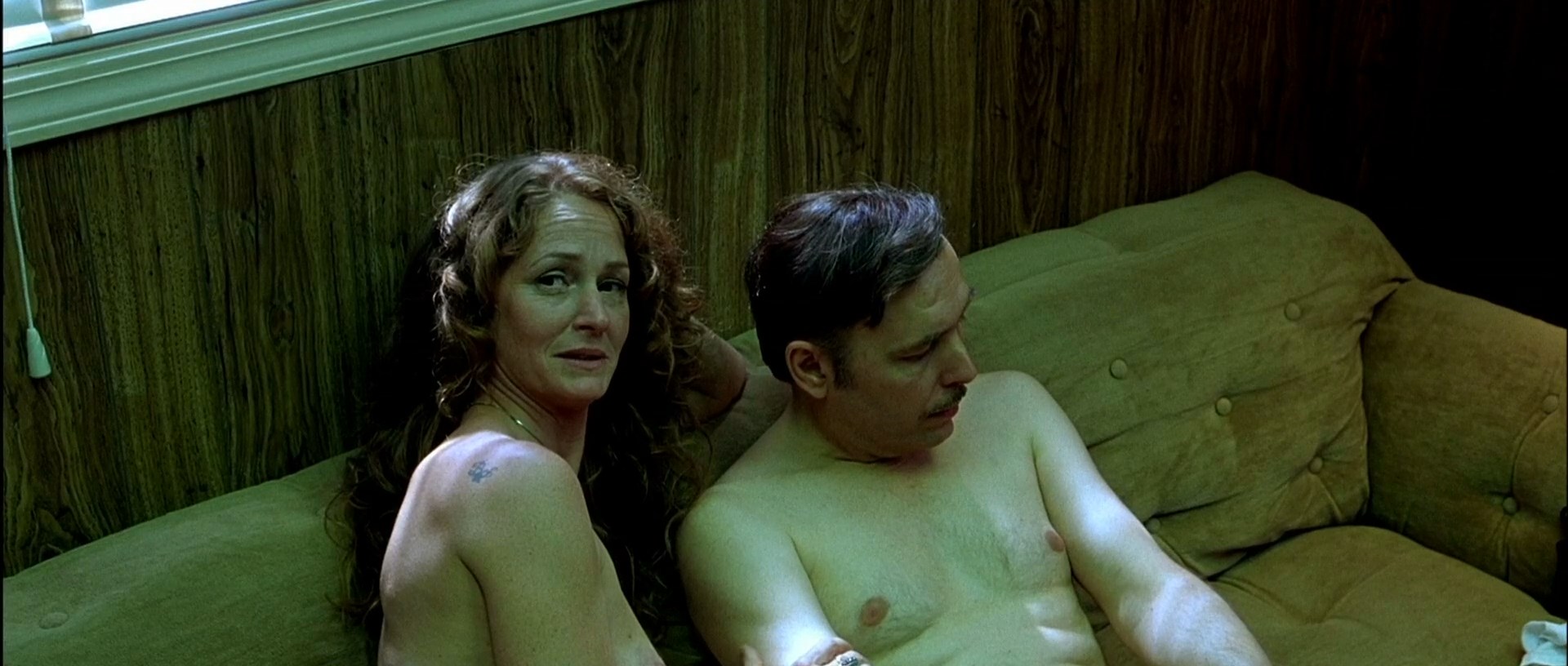 Melissa Leo is sitting naked in a sofa with some guy.