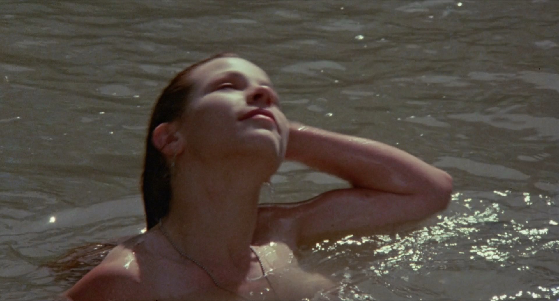 Lili Taylor is swimming topless while two dudes ogle her.
