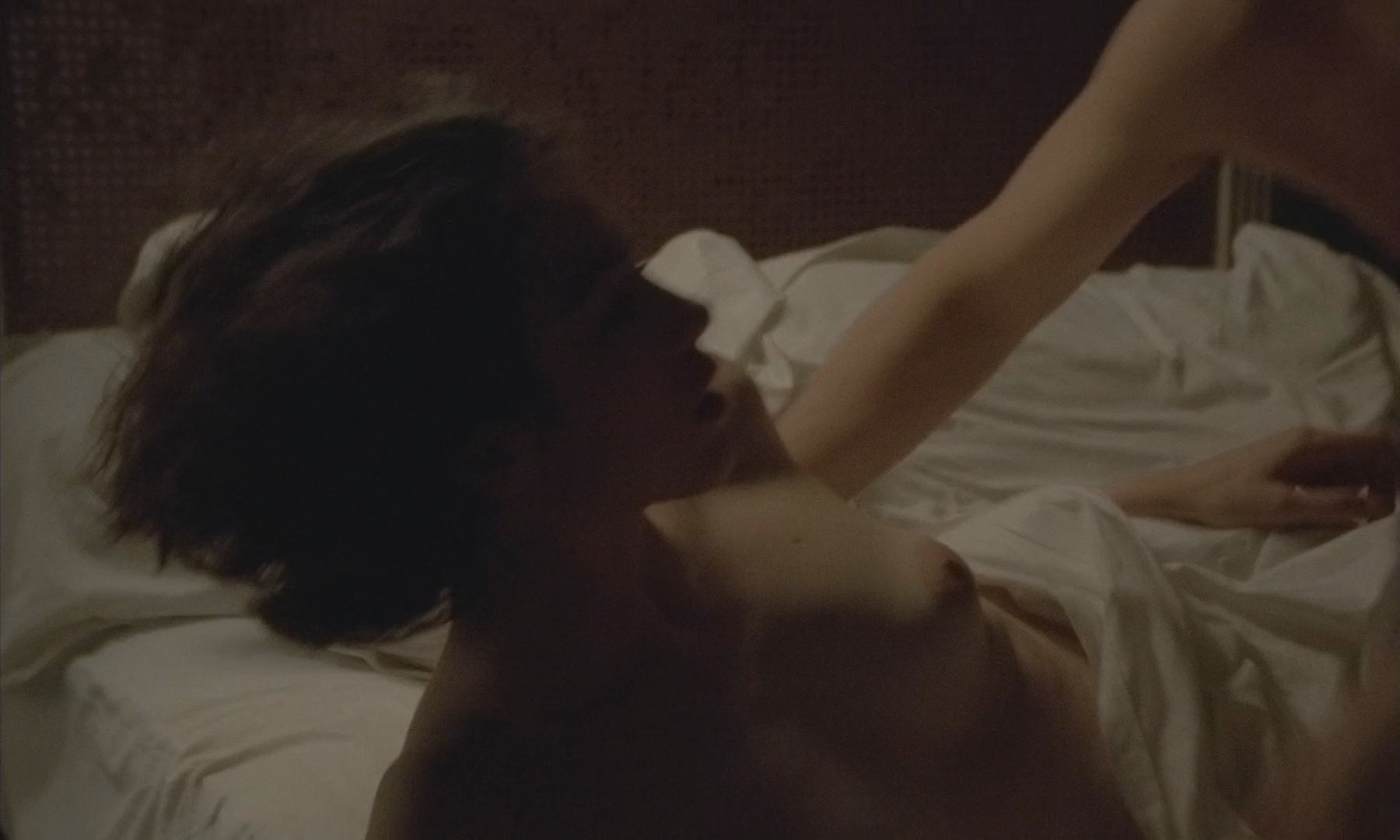 Isabelle Adjani is laying topless on the bed. 