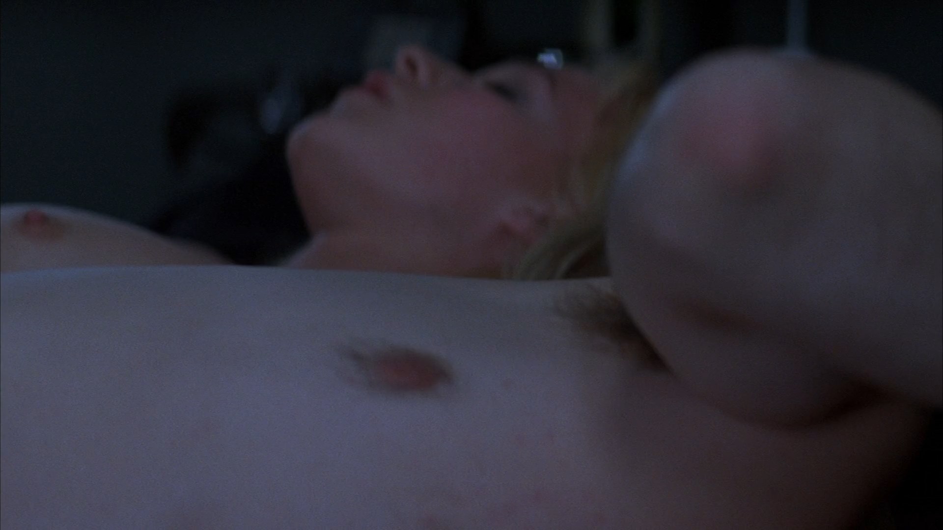 Franka Potente shows her tits while laying on the bed next to some guy. 