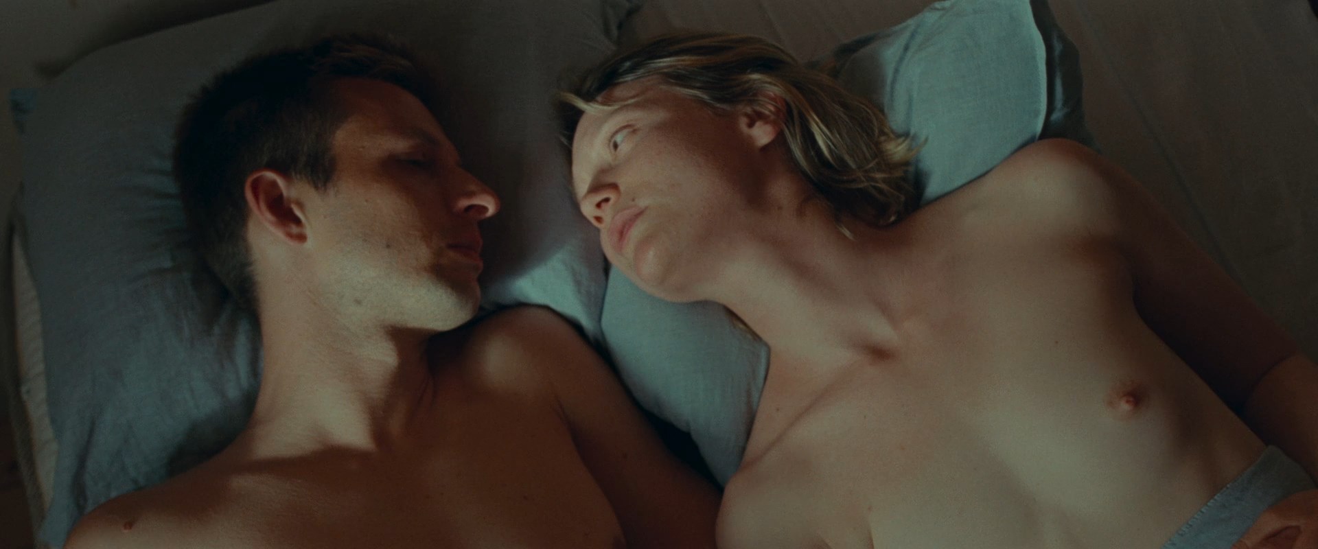 Mia Wasikowska is laying topless next to some guy.